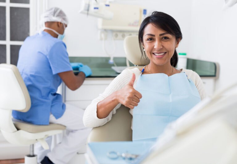 Satisfied Latina in dental office showing thumbs up after treatment